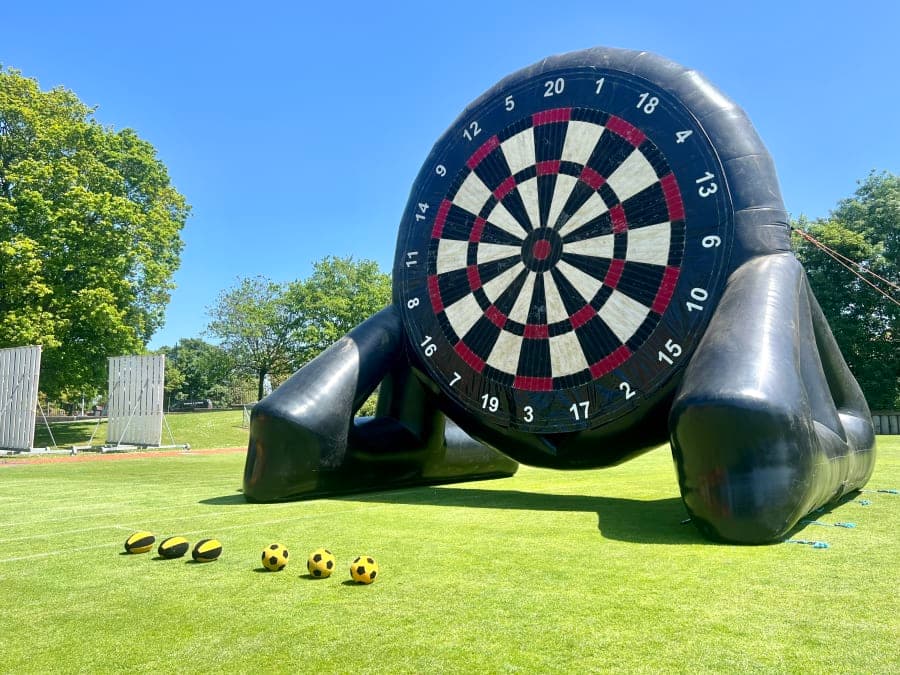 Players kicking Velcro balls at a giant inflatable football dartboard